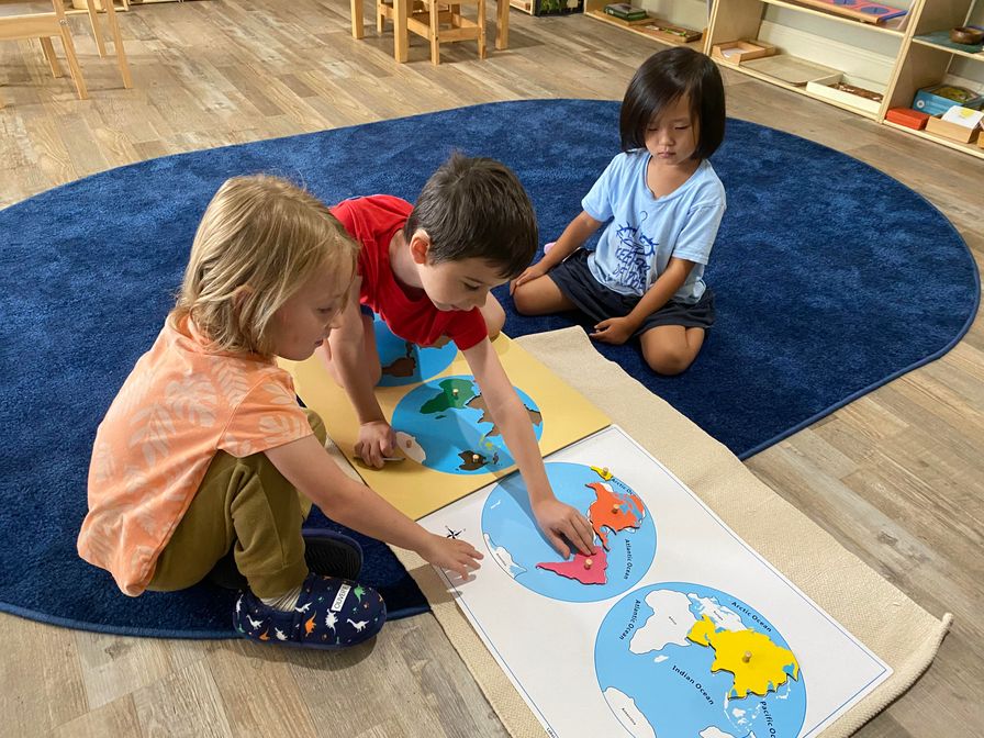 Three children arrange the continents on earth models