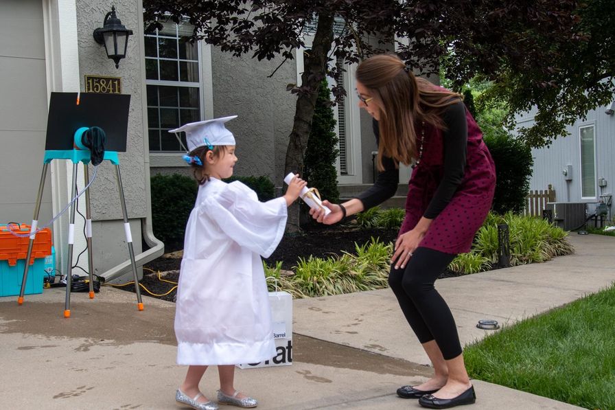 A child graduates, receiving a diploma from Guide/Teacher Emily